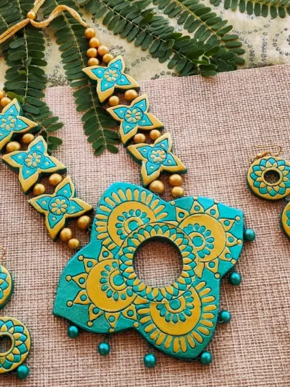 A unique butterfly-shaped pendant with a mandala design in sea green and gold. This set comes with two layers of hanging earrings.