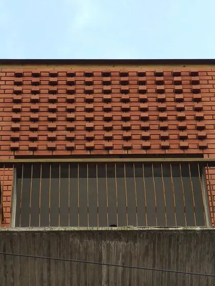 A detail of the patterned exposed brickwork on the Earthen Anthem apartment building, creating texture and shadow play on the facade.