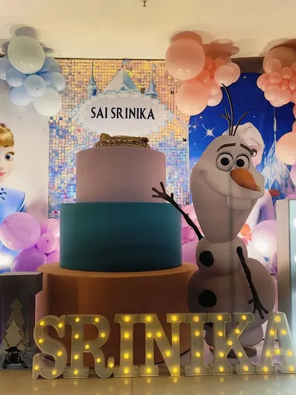 A close-up of the cake area for the Frozen party, with a three-tier cake and an Olaf prop.