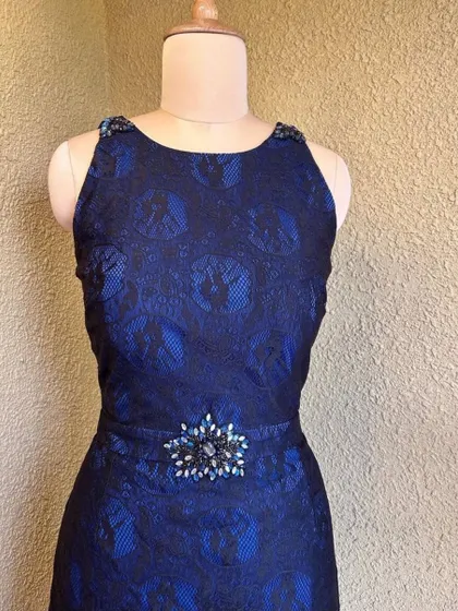 The dress features elegant embellishments on the shoulders and waist, adding a touch of sparkle.