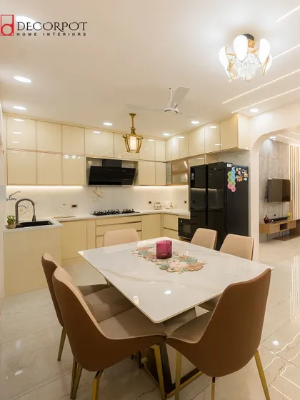 This luxurious kitchen and dining area features cream-colored high-gloss cabinets and a large dining table. The open layout is perfect for families who love to cook and eat together.