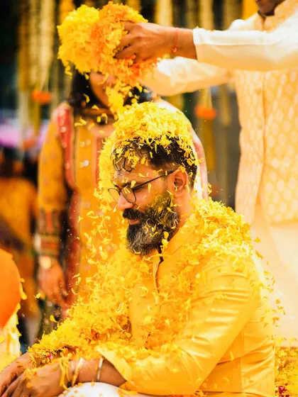 The groom gets his turn during the Haldi ceremony, showered with a cascade of yellow marigold petals. A vibrant and essential part of the Indian wedding tradition.