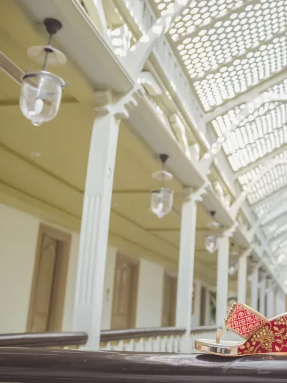 An artistic still-life of the groom's traditional wedding shoes (mojari) resting on a balcony railing. This shot highlights the small but significant details of the groom's attire.