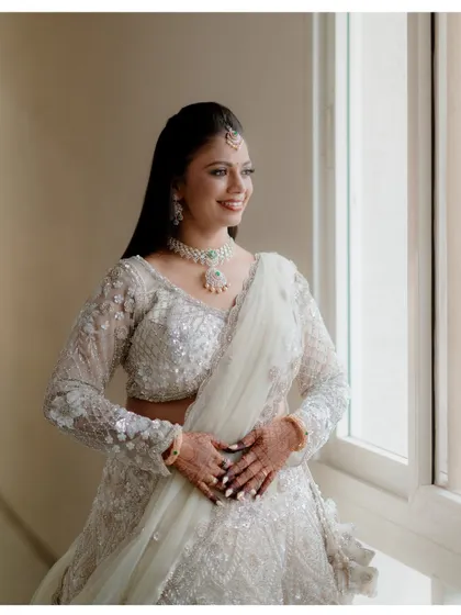 A beautiful portrait of the bride, Shreya, looking out the window before her reception. The natural light highlights her features and elegant attire.