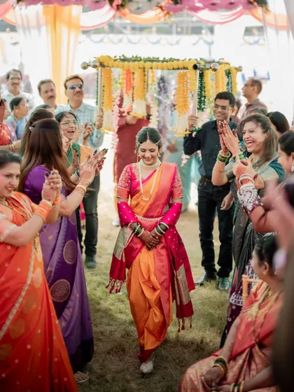 The bride's joyful entrance, surrounded by clapping family and friends, a classic moment in a Maharashtrian wedding.