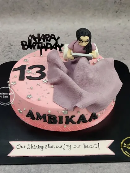 An "Official Teenager" cake for a 13th birthday. This pink cake features a figurine of a girl reading, capturing a moment of transition into the teen years.