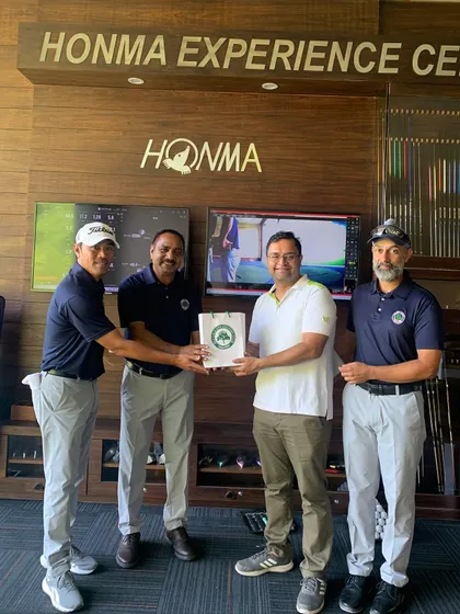 An Instructor Presenting an Award at the Men's Golf Camp: We celebrate progress and achievement at every level. An instructor presents a prize to a participant during the closing ceremony of the Men's Golf Camp, recognizing their performance in the camp's challenges.