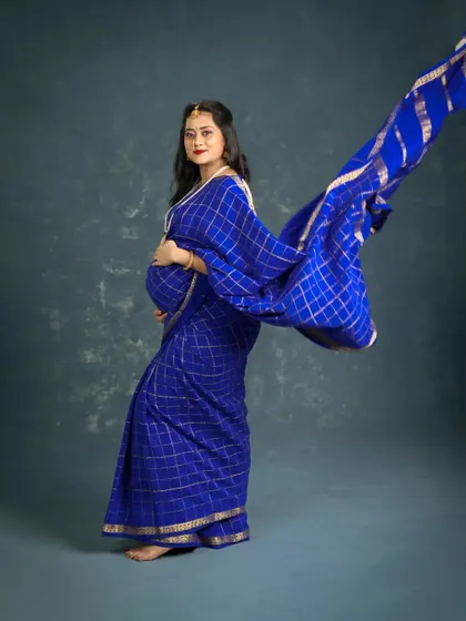 A striking portrait of a mom-to-be in a royal blue saree. The flowing fabric creates a sense of movement and drama, making for a powerful and artistic traditional maternity photo.