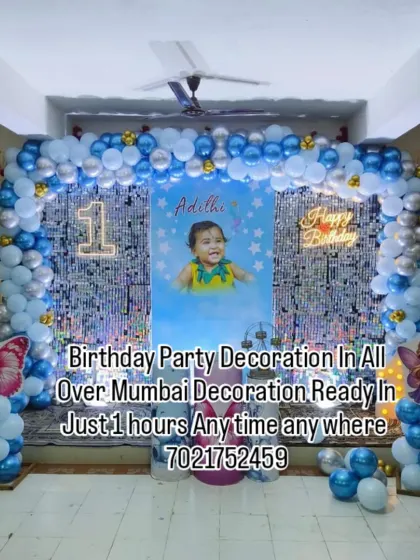 Make your child's first birthday extra special with a personalized photo backdrop. This blue and silver balloon arch frames a large poster of the birthday baby, creating a beautiful memory.
