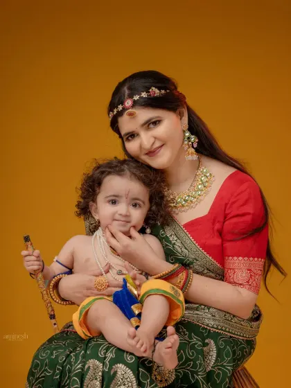 A classic portrait where a mother holds her baby Krishna, both looking at the camera. This is a perfect way to capture your bond during the festive season.
