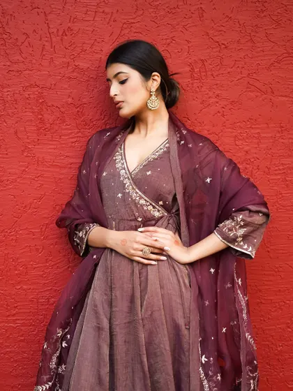 The rich maroon of this angrakha-style suit is captured with a soft, flattering light. This three-quarter shot focuses on the intricate silver embroidery on the bodice and dupatta.