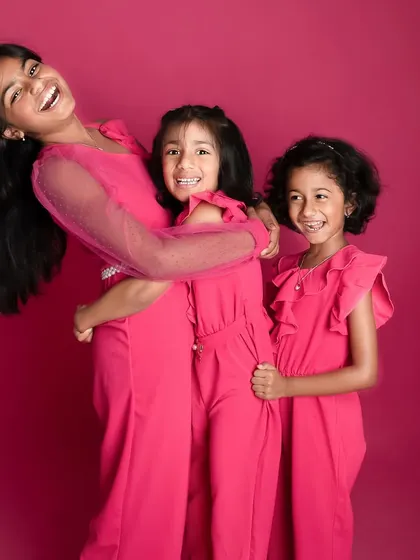 The energy of these three sisters is just infectious. Using a vibrant pink backdrop makes their joyful personalities pop in this fun sibling photoshoot.