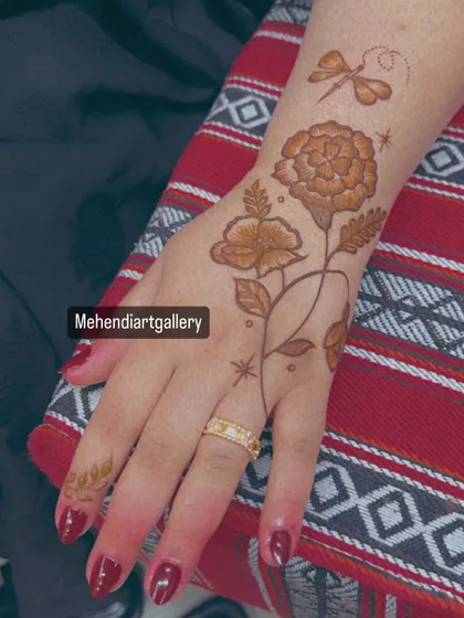The full view of the dragonfly and floral mehendi on the back of the hand. The placement creates a beautiful, flowing composition.