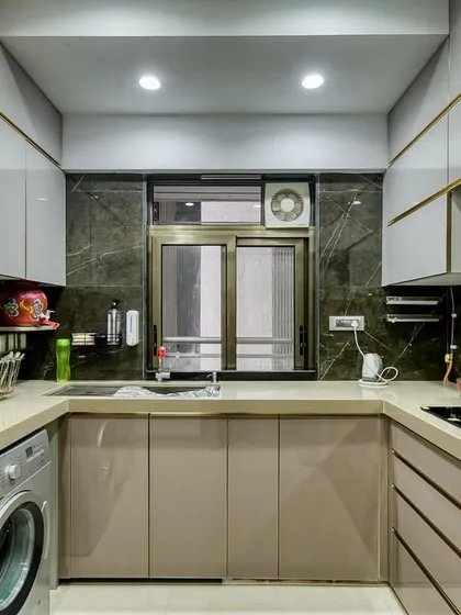 An elegant C-shaped acrylic kitchen with gold-toned profiles. The design includes integrated appliances and a washing machine, showcasing our ability to create highly functional and customized layouts.
