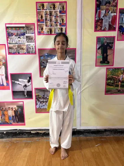 With a smile of accomplishment, this student displays her certificate for advancing to the next taekwondo grade. Each certificate is a testament to her dedication and hard work.
