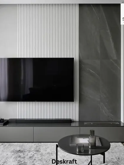 A modern minimalist living room featuring a striking TV wall that combines textured white panels with a dark marble accent, creating a sophisticated focal point.