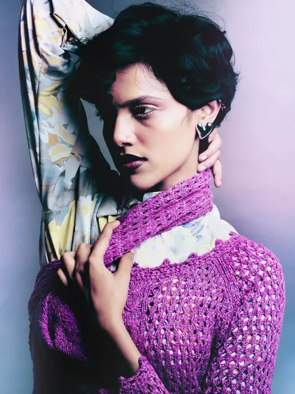 A close-up portrait from 'My Flatmate's Wardrobe,' focusing on the layered knitwear and floral shirt. The soft lighting and dark lipstick create a moody, stylish look.