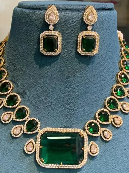 This single-layer Victorian necklace with a large rectangular green stone is a statement piece. It comes with matching earrings and is perfect for a minimalist but bold look.