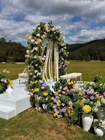 A stunning outdoor floral arch made with a mix of colorful flowers, set against a beautiful natural landscape.