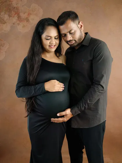 An elegant and moody portrait of a couple in matching black outfits, sharing a quiet and intimate moment.