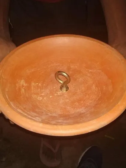 A close-up of a custom-made earthen pot with a brass hook, a small but crucial detail designed to support hanging planters or bird nests.