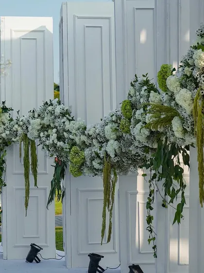 A detail of the cascading floral garlands that adorned the entrance structure. Composed of white flowers and fresh greenery, they created a lush, organic frame for the gateway to the celebration.
