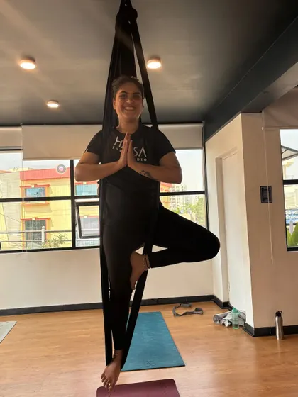 A student finds her balance in a standing tree pose variation using the hammock for support. This is a great way to build stability and confidence.