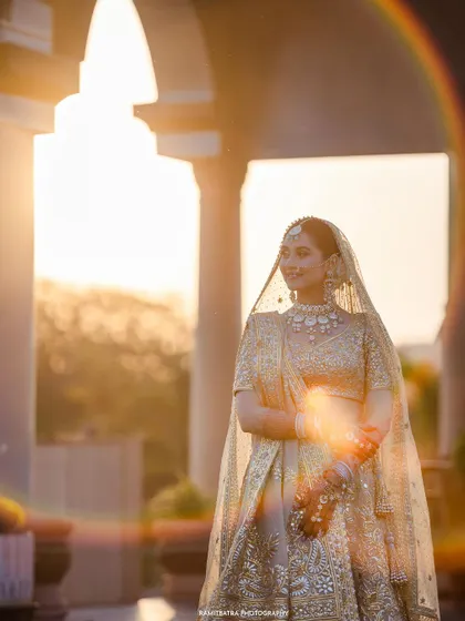 The bride is bathed in the golden hour light, with a rainbow lens flare adding a touch of magic to her portrait.