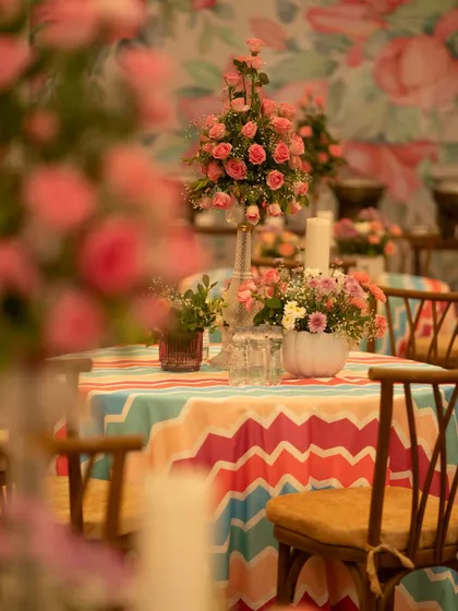 A beautiful table setting with a vibrant chevron-patterned tablecloth and a centerpiece of pink roses. The mix of bold patterns and soft florals creates a playful yet elegant look.