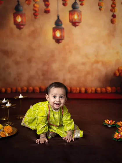 A wide shot capturing the baby crawling amidst the beautiful Diwali decor, with diyas and marigolds creating a warm atmosphere.