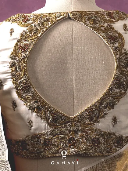 The back of the ivory blouse reveals a dramatic and beautifully embroidered keyhole design. This feature adds a touch of modern design to the traditional ensemble, framed by exquisite handwork.