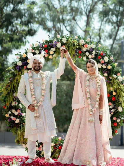 The couple shares a moment of triumph and joy after their wedding ceremony, standing under a beautiful floral arch. This photo perfectly captures the feeling of "we did it!".