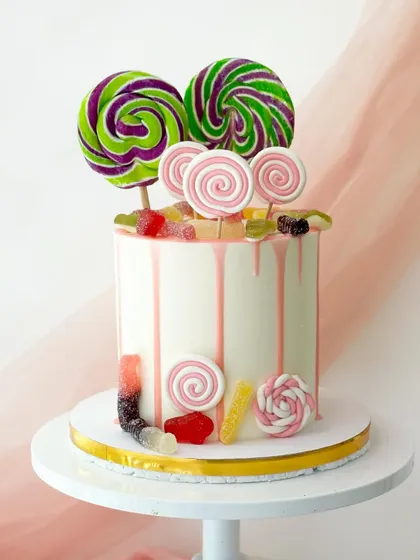 A candy drip cake that's pure fun. The white buttercream cake has a pink drip and is loaded with real and fondant candies and lollipops.