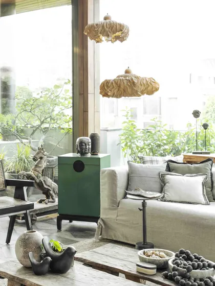 An Oorjaa light installation made of natural fibers hangs in the conservatory, adding to the room's organic and peaceful charm. The space is a testament to the beauty of imperfection and natural materials.