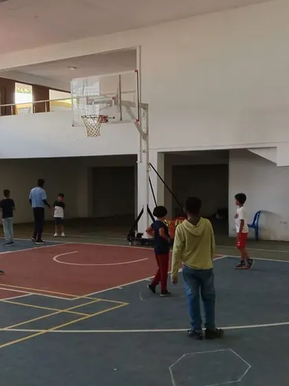 Students engage in a friendly game of basketball, learning teamwork and sportsmanship in our well-equipped indoor facility.