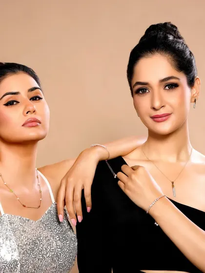 Two models posing together, showcasing a collection of modern, minimalist chains and bracelets for a contemporary brand.