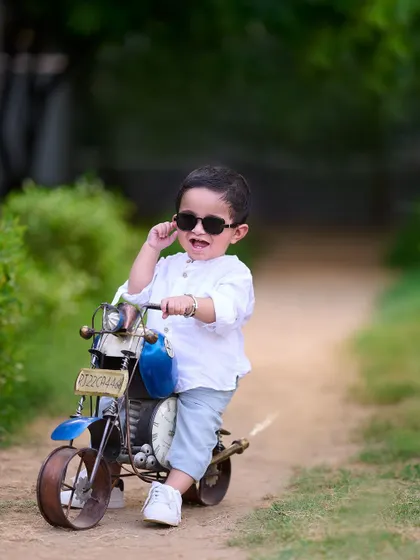 This little hero is ready to hit the road in style. Adding simple props like sunglasses can completely change the vibe of a photo and add a dose of cool personality.
