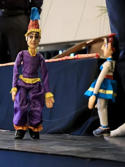 Another view of the live string puppet demonstration on stage. The puppets, though small, command the attention of the entire room with their lifelike movements.
