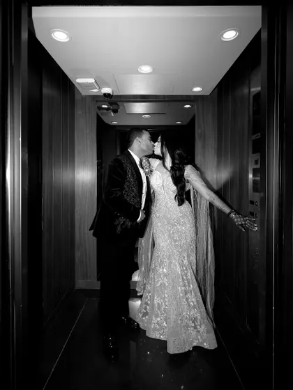 A classic black and white shot of a kiss in a hotel corridor. This timeless photo captures a stolen, romantic moment away from the crowd.