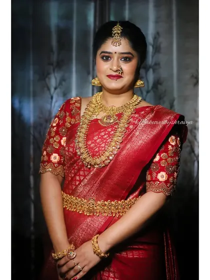 This bride looks regal in her deep red wedding saree. The makeup is classic and elegant, with warm tones on the eyes and lips to complement the rich colour of her outfit and gold jewellery.