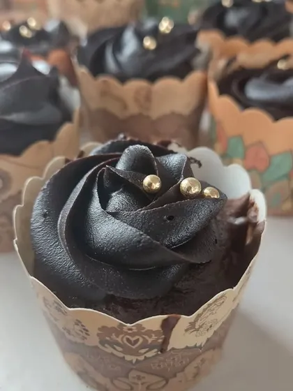Decadent chocolate cupcakes with gold sprinkles, prepared as a special snack for a corporate event. These bite-sized treats are always a crowd-pleaser.