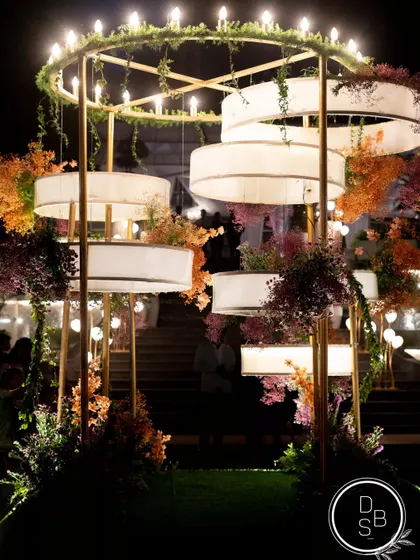 A detailed shot of the custom light installation at the reception. The tiered design, wrapped in fabric and florals, created a stunning focal point as night fell.
