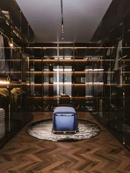 A stunning walk-in closet with dark wood, glass doors, and integrated lighting. This luxurious design provides ample space for clothes, shoes, and accessories, all beautifully displayed.