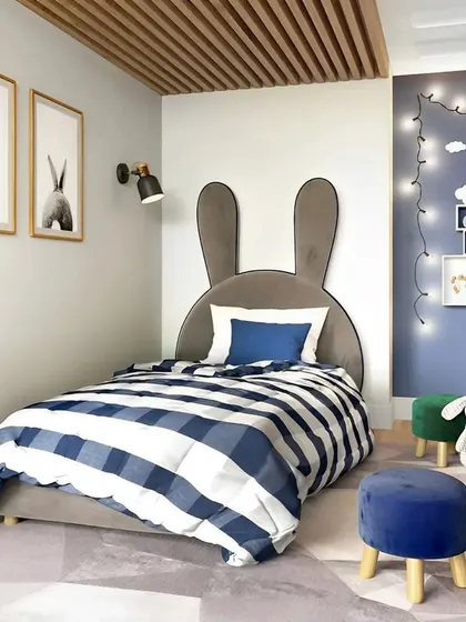A sweet and simple kids' room with a bunny-themed headboard. The fairy lights and house-shaped shelves on the blue accent wall add a touch of magic.