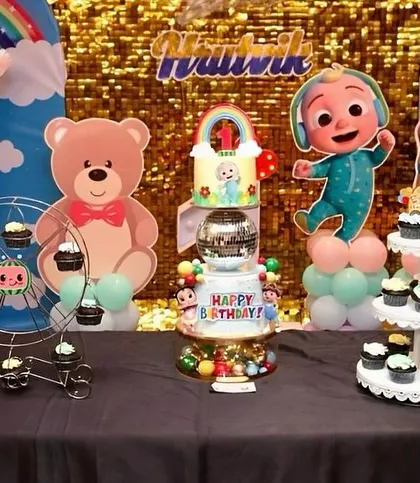 A wide shot of the Cocomelon dessert table, showing the main cake, cupcakes on a ferris wheel, and a cupcake stand.