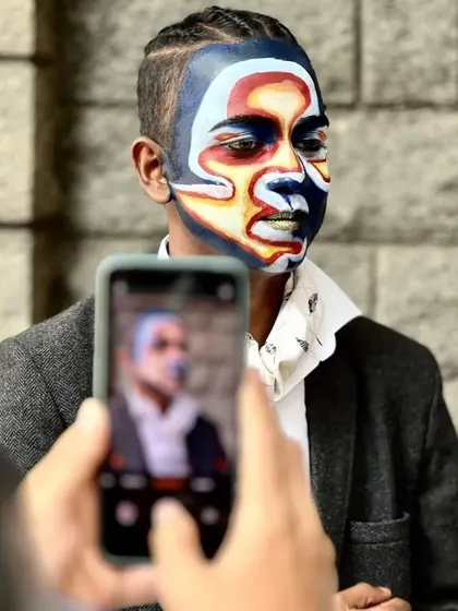 A candid shot of the abstract face paint model being photographed, showing the real-world impact of the artwork.