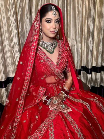 A traditional Indian bridal look featuring kohl-lined eyes and a dewy skin finish. This makeup is designed to complement the classic red Sabyasachi lehenga, creating a look that is both timeless and beautiful.