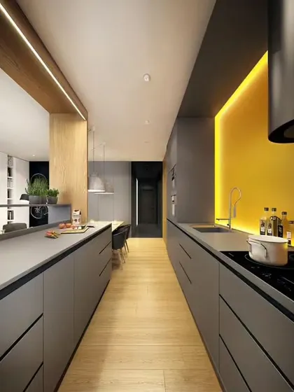 This long parallel kitchen uses minimalist grey cabinets and a yellow accent wall to create visual interest. The design emphasizes clean lines and an uncluttered feel.