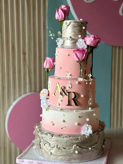 Elegance layered high. This stunning pink, silver, and white wedding cake features multiple tiers with different textures, from shimmering silver to soft pink, all adorned with fresh roses.