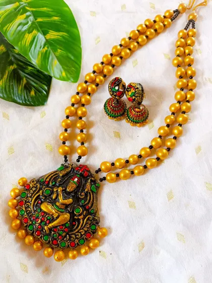 This stunning terracotta set features a detailed depiction of Murli Manohar, or Krishna with his flute. It's a masterpiece of temple jewelry, perfect for Janmashtami and other devotional occasions.